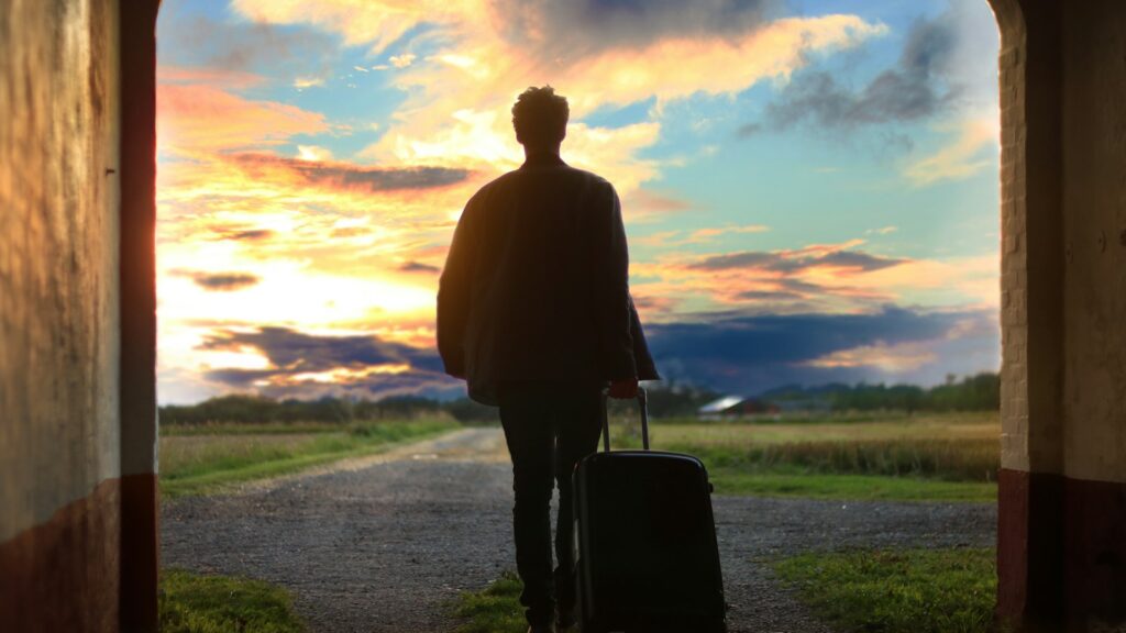 Traveler with a suitcase walking out toward a sunrise